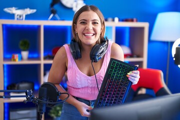 Canvas Print - Young blonde woman playing video games holding keyboard smiling and laughing hard out loud because funny crazy joke.