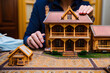 A miniature model of a finely detailed wooden house on display as a woman put on some finishing touches. An artist working on building a scaled diorama in an arts and handicraft project. Generative Ai