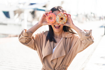 Wall Mural - Young woman at outdoors holding donuts in an eye