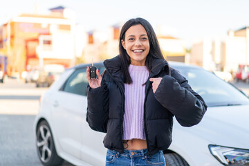 Wall Mural - Young woman at outdoors holding car keys at outdoors with surprise facial expression