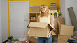 © Krakenimages.com - Young blonde woman smiling confident holding package at new home