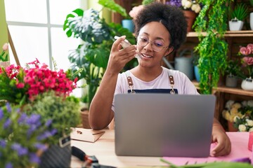 Poster - African american woman florist talking on smartphone using laptop at flower shop