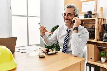 Sticker - Middle age grey-haired man architect talking on smartphone eating sushi at office