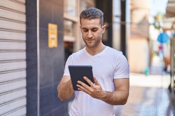 Sticker - Young caucasian man using touchpad with relaxed expression at street