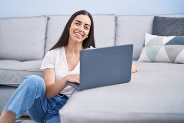 Poster - Young hispanic woman using laptop sitting on floor at home