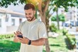 © Krakenimages.com - Young hispanic man smiling confident using smartphone at park