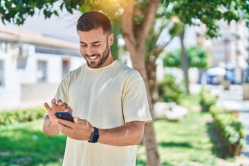 Poster - Young hispanic man smiling confident using smartphone at park