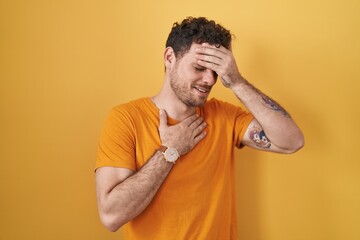 Sticker - Young hispanic man standing over yellow background touching forehead for illness and fever, flu and cold, virus sick