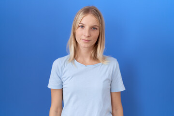 Poster - Young caucasian woman wearing casual blue t shirt relaxed with serious expression on face. simple and natural looking at the camera.