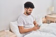 © Krakenimages.com - Young arab man listening to music sitting on bed at bedroom