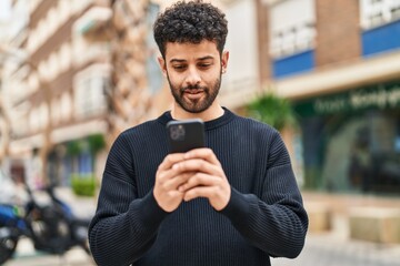 Wall Mural - Young arab man smiling confident using smartphone at street