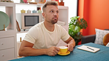 Canvas Print - Young man drinking coffee sitting on table thinking at dinning room