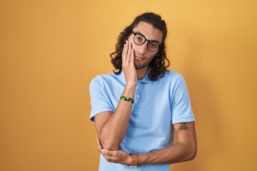 Poster - Young hispanic man standing over yellow background thinking looking tired and bored with depression problems with crossed arms.