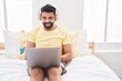 © Krakenimages.com - Young arab man using laptop and headphones sitting on bed at bedroom