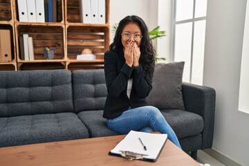 Canvas Print - Young asian woman at consultation office laughing and embarrassed giggle covering mouth with hands, gossip and scandal concept