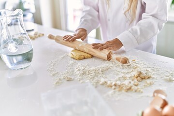 Canvas Print - Young woman wearing cook uniform kneading pasta dough at kitchen