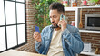 © Krakenimages.com - Young latin man arguing on smartphone holding credit card at dinning room