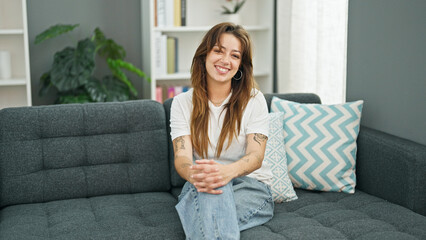 Sticker - Young beautiful hispanic woman smiling confident sitting on sofa at home