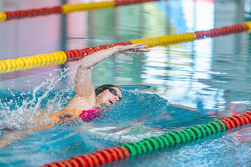 Elite female athlete, professional swimmer during a front crawl swimming workout. Concept of hard training for a competition.