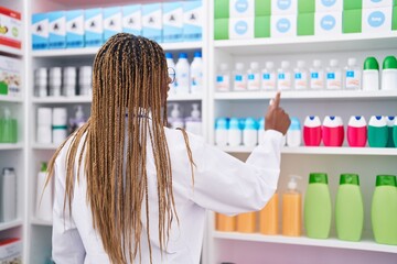 Poster - African american woman pharmacist holding deodorant of shelving at pharmacy