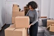 © Krakenimages.com - Young beautiful hispanic woman smiling confident holding package at new home