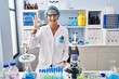© Krakenimages.com - Brunette woman working at scientist laboratory smiling positive doing ok sign with hand and fingers. successful expression.