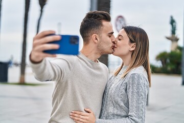 Wall Mural - Man and woman couple make selfie by smartphone kissing at street