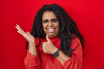 Sticker - Plus size hispanic woman standing over red background showing palm hand and doing ok gesture with thumbs up, smiling happy and cheerful