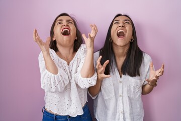 Wall Mural - Hispanic mother and daughter together crazy and mad shouting and yelling with aggressive expression and arms raised. frustration concept.