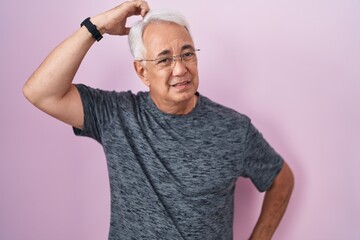 Poster - Middle age man with grey hair standing over pink background confuse and wondering about question. uncertain with doubt, thinking with hand on head. pensive concept.