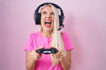 Poster - Caucasian woman playing video game holding controller angry and mad screaming frustrated and furious, shouting with anger looking up.