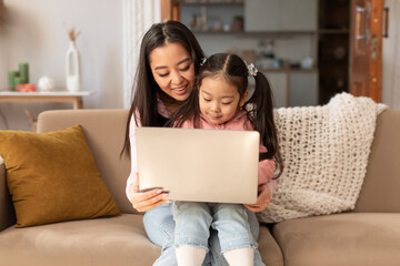 Wall Mural - Young Asian Woman With Baby Daughter Using Laptop At Home