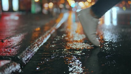 Wall Mural - legs of a girl taking a step into a puddle on the street of a night city