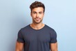 © Tuyres - Portrait of a muscular handsome guy wearing a plain navy blue t-shirt, isolated on a light blue pastel background. Generative AI illustration.
