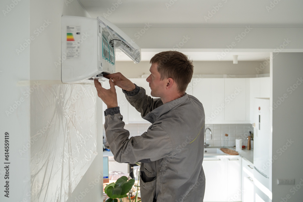 Young man technician worker in uniform fixing repairing apartment air ...