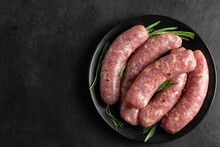 Raw Sausages Or Bratwurst With Spices And Rosemary In A Plate On Black Background. Top View