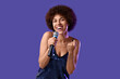 © New Africa - Curly young woman with microphone singing on purple background