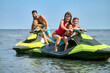 © zinkevych - Father, mother, daughter and son racing on jet-skis enjoying watercraft in ocean.