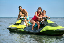 Father, Mother, Daughter And Son Racing On Jet-skis Enjoying Watercraft In Ocean.