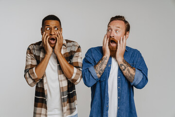 Wall Mural - Two shocked male friends grabbing their heads with mouths open