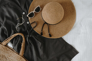 Wall Mural - Aesthetic fashion composition with female clothes and accessories. Black linen shirt and shorts, sunglasses, straw hat, rattan handbag. Flat lay, top view