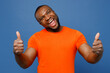 © ViDi Studio - Young smiling happy cool man of African American ethnicity he wears orange t-shirt showing thumb up like gesture isolated on plain dark royal navy blue background studio portrait. Lifestyle concept.