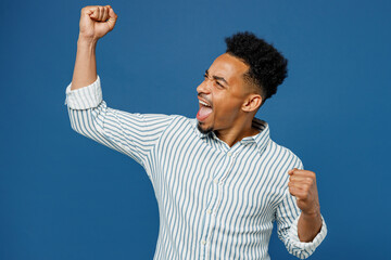 Wall Mural - Young man of African American ethnicity he wear casual clothes shirt doing winner gesture celebrate clenching fists say yes isolated on plain dark royal navy blue background studio. Lifestyle concept.