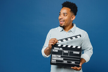 Sticker - Young man of African American ethnicity he wears casual clothes shirt hold in hand classic black film making clapperboard isolated on plain dark royal navy blue background studio. Lifestyle concept.