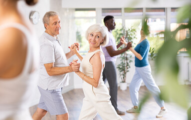 Wall Mural - Mature man dances steamy salsa with elderly female companion for fitness classes and enjoys movement and activity. Hobbies, active pastime