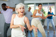 © JackF - Young girl coach conducts classes for elderly in fitness studio. Female instructor teaches senior students of different ages dance class basic movements of contemporary dances