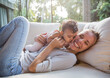 © Westend61 - Happy mother having fun with daughter on sofa in living room at home