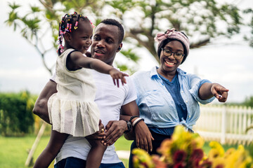 Wall Mural - Portrait of enjoy happy love black family african american father and mother with little african girl child smiling and play having fun moments good time in park at home