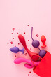 © Goncharuk film - Concept of erotic pleasure toys. Top view vertical arrangement of shopping bag, vibrators, anal plugs, vaginal balls, red hearts on pastel pink background with empty space for text or advert