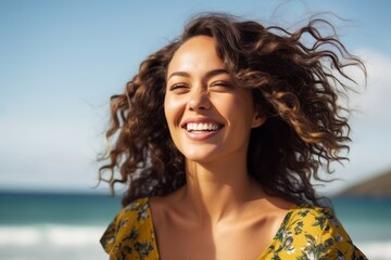 Wall Mural - Portrait of a smiling young woman with curly hair on the beach